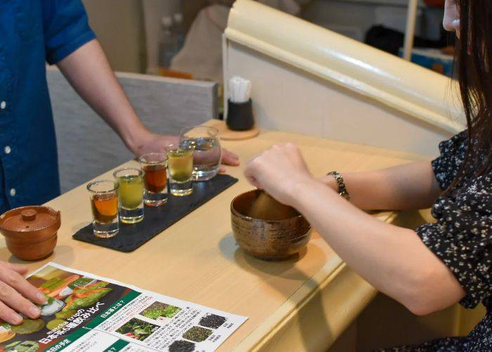 Shot glasses filled with five different types of traditional Japanese tea, perfect for trying the different flavors.